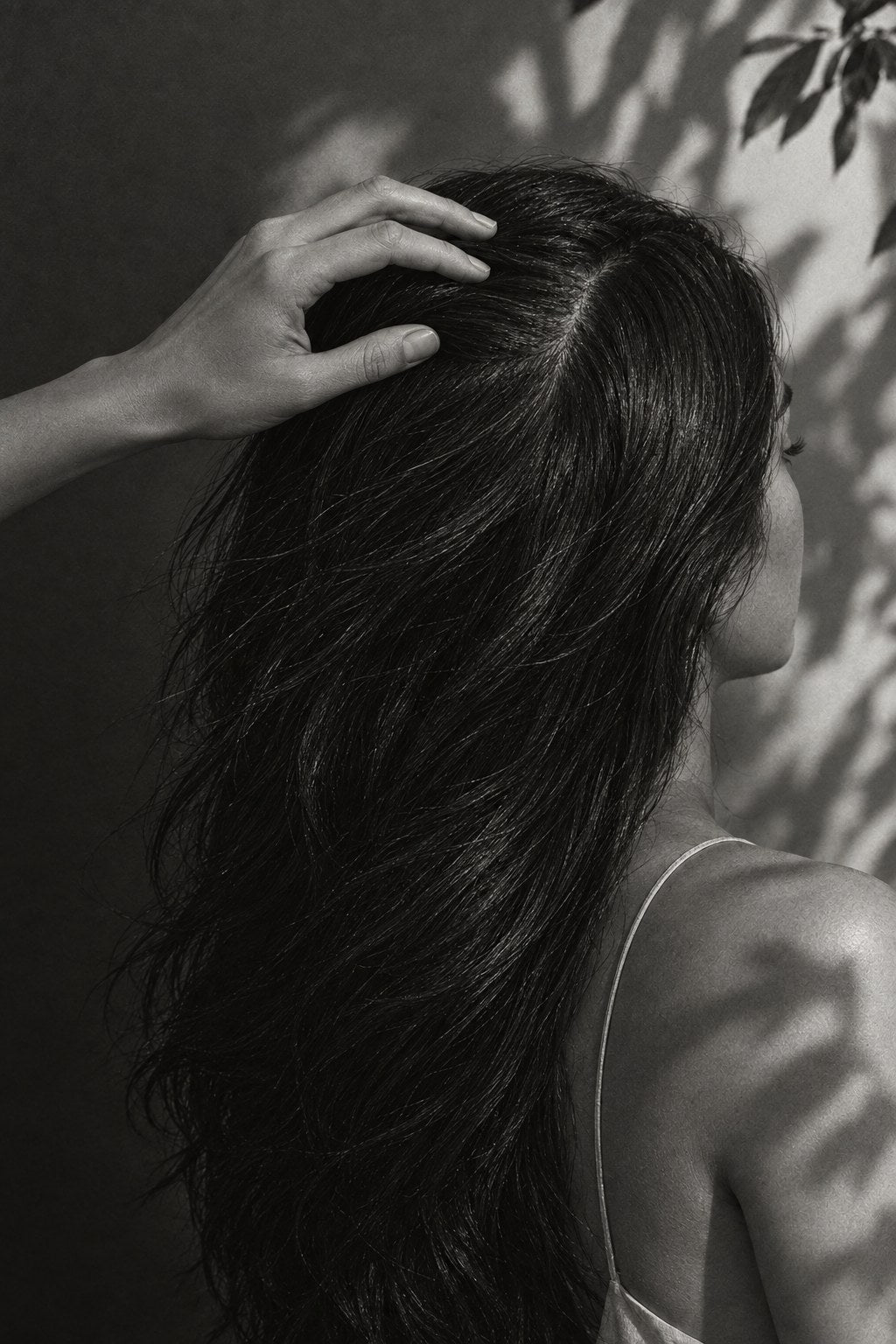 Hand gently parting long dark hair to show the scalp